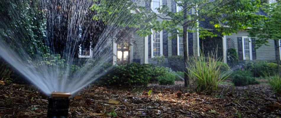 Irrigation sprinkler head in Cary, NC, spraying water over a landscape.