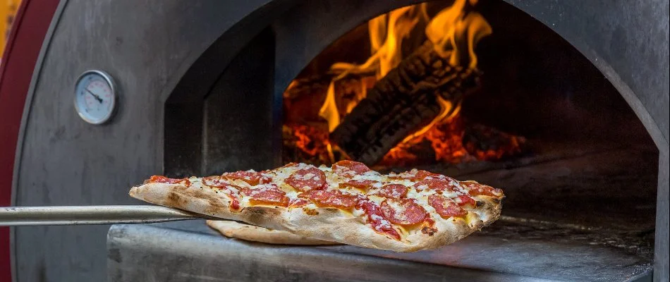 Inserting a pizza into a pizza oven in Cary, NC.